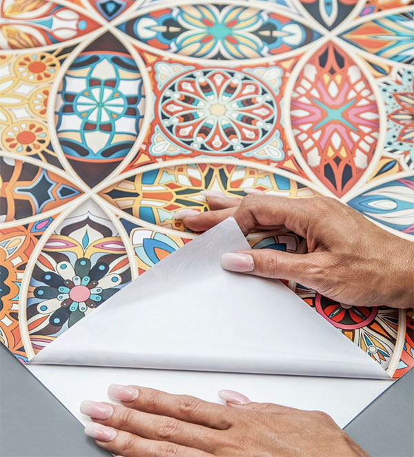 Close-up of colourful patterned peel and stick wallpaper being peeled back to show the adhesive backing.