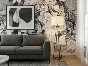 A zoom-in of Noir Botanical wallpaper with large hand-drawn floral outlines in black, ivory, and grey, styled with a charcoal sectional sofa, abstract wall art, and soft neutral decor.