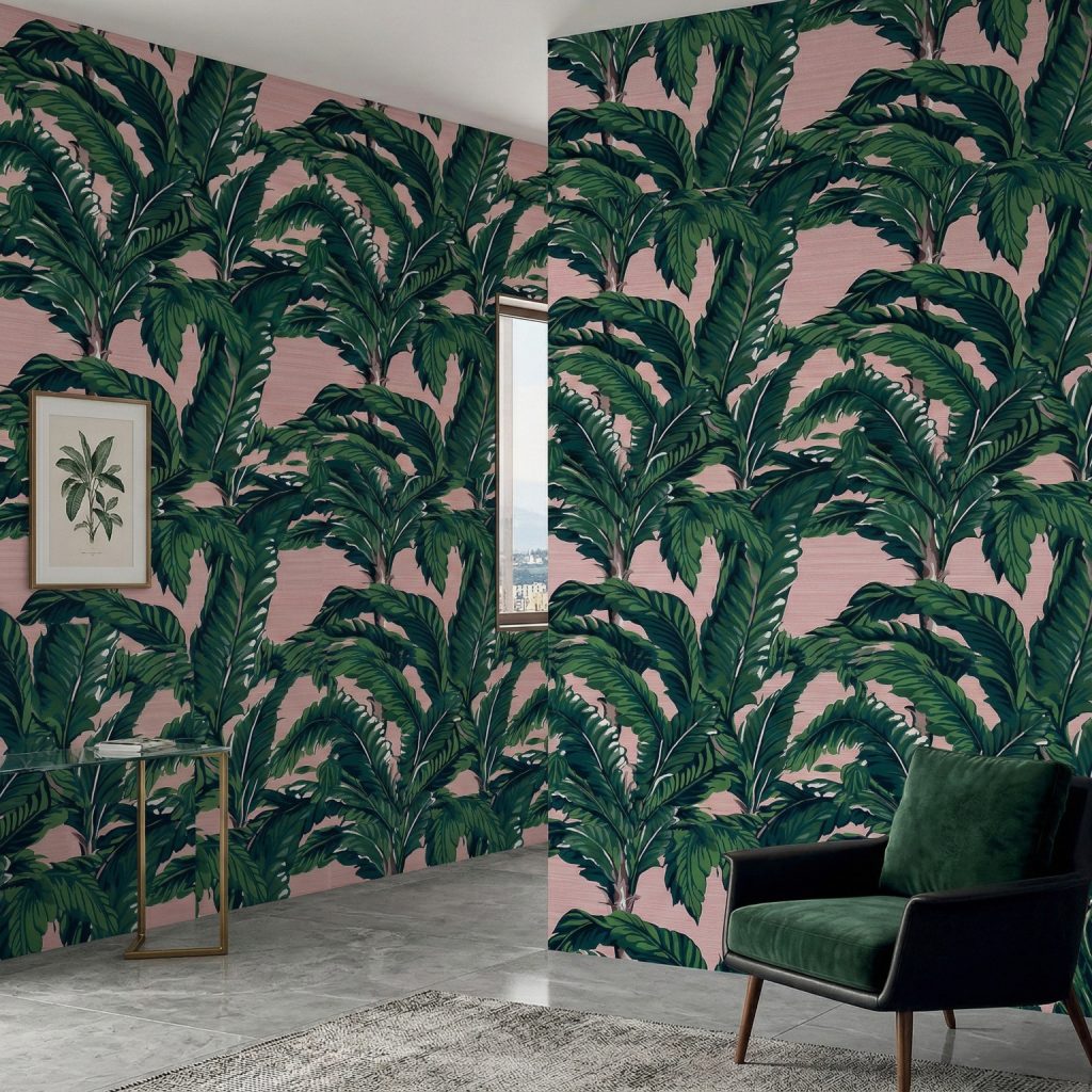Blush banana leaf wallpaper installed in a modern corner space with framed botanical art and green velvet armchair.