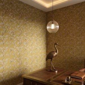 A zoomed-in of hite blossoms wallpaper in an ochre home office.